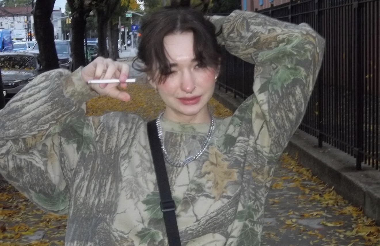 Anna on a quiet fall street in an oversized camo sweatshirt